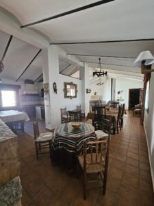 Sofá de tres plazas y dos sillones tapizados en tela beige, chimenea y comedor.