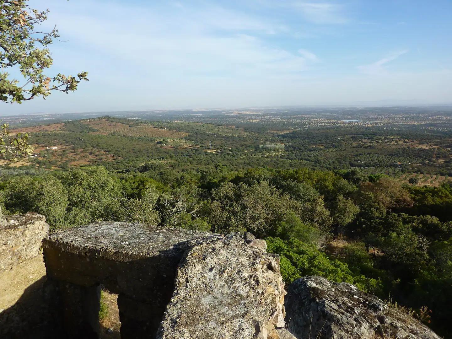 Impresionantes vistas panorámicas de la campiña cordobesa desde la cima de Peña Ladrones, en Villanueva del Duque. Se observan extensos campos de olivos, pueblos blancos y la Sierra Morena al fondo. Un cielo azul intenso completa la escena. (Villanueva del Duque, Córdoba, España)
